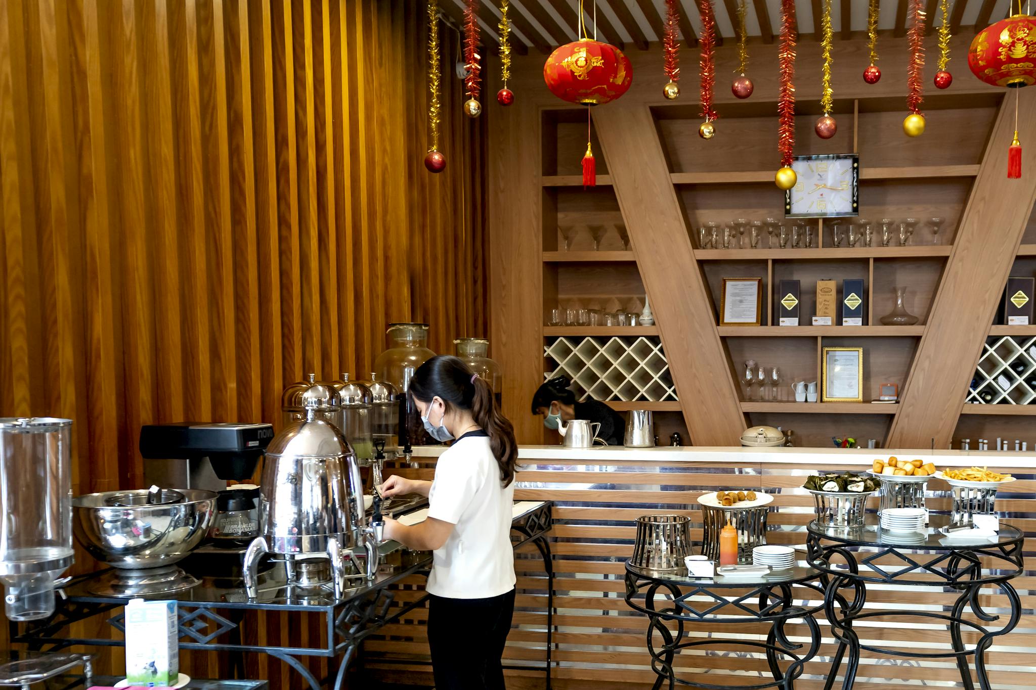A modern buffet with festive decor and a person serving coffee, showcasing a sleek restaurant design.
