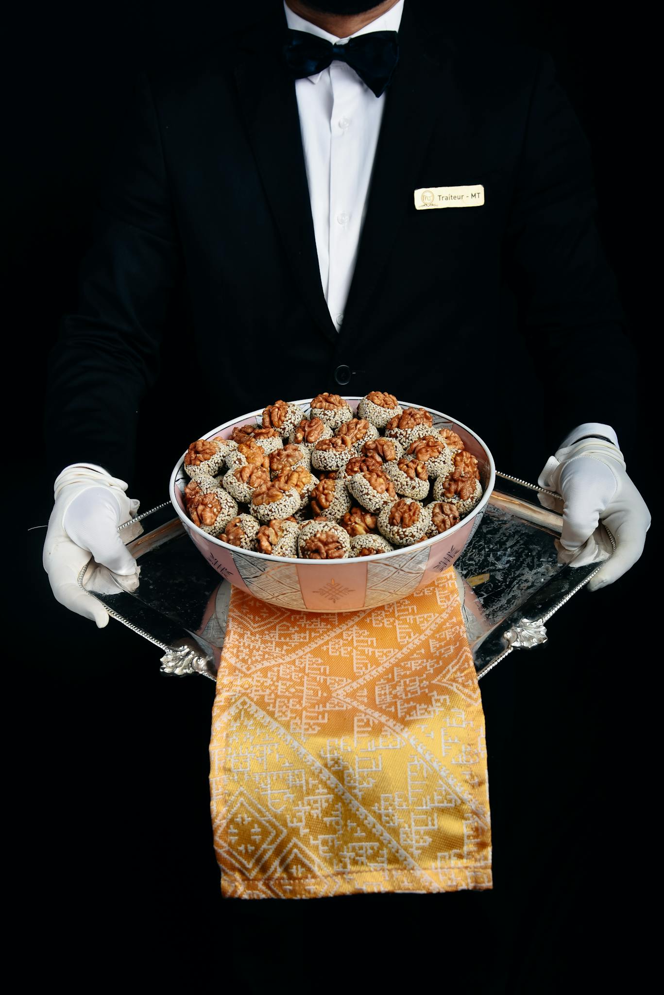 A waiter presents gourmet appetizers on a silver tray, showcasing elegant hospitality.