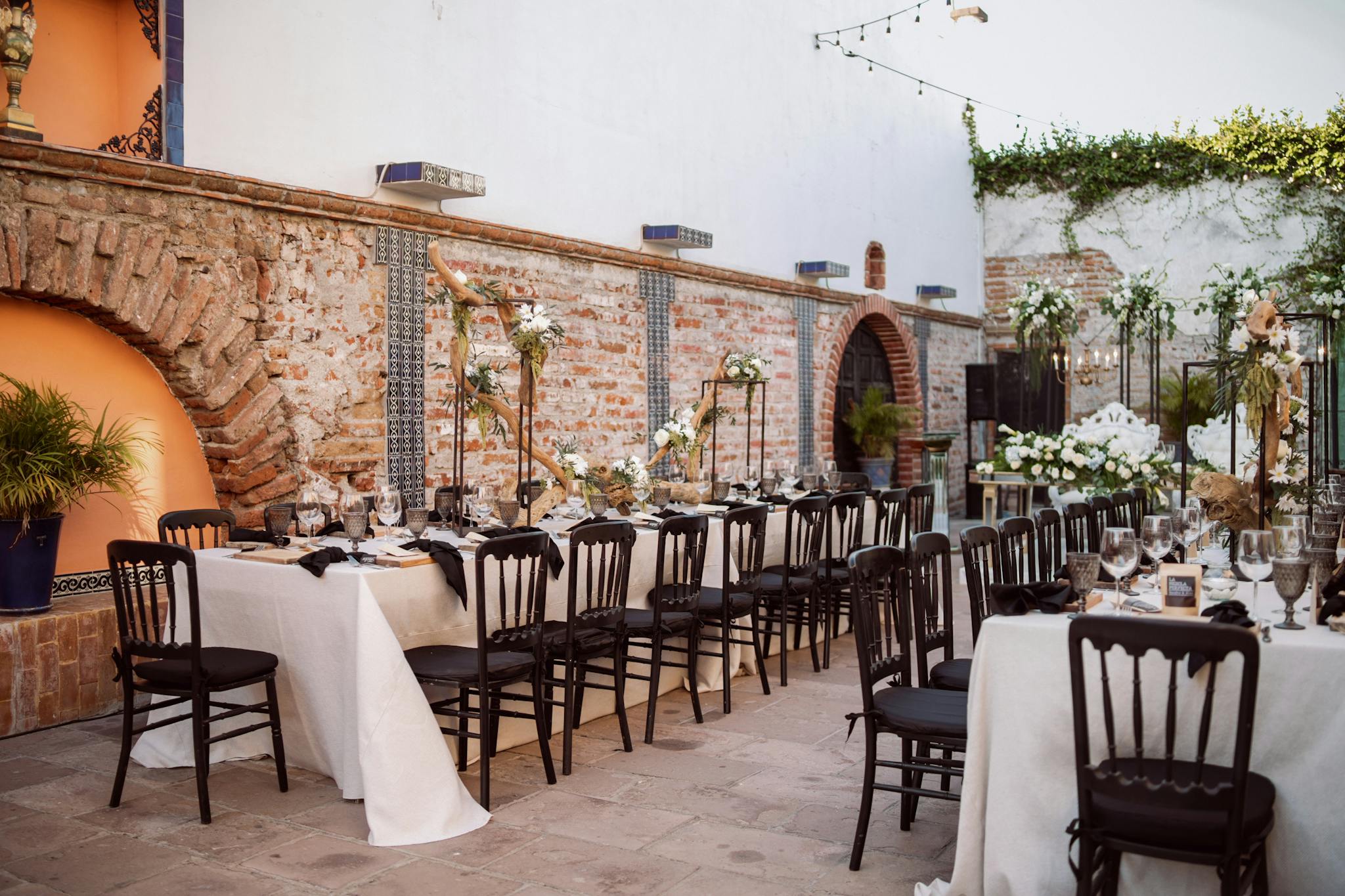 Chic outdoor wedding venue with decorated tables, chairs, and floral arrangements.