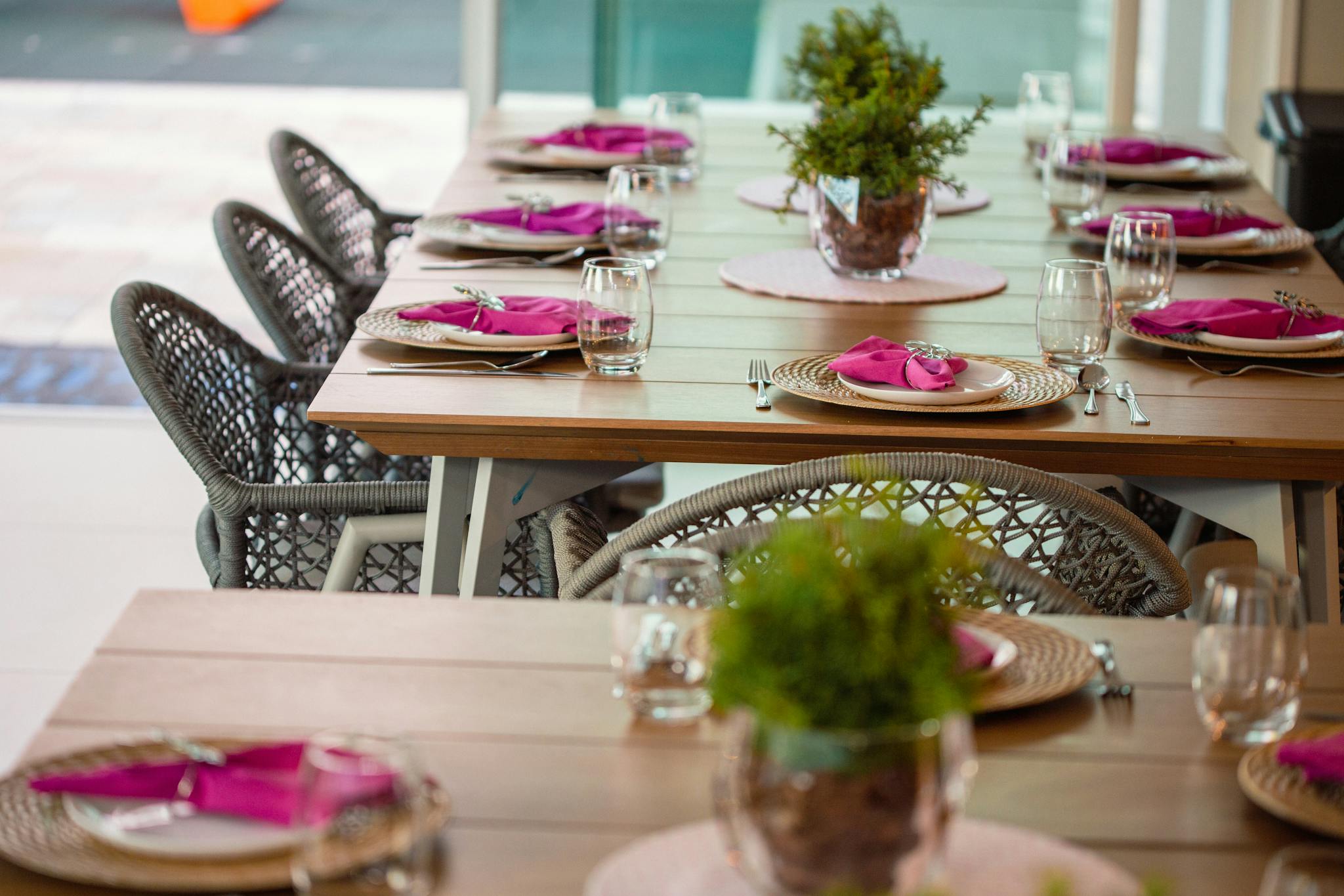 Stylish table setting with wicker chairs and pink napkins, ideal for indoor dining.